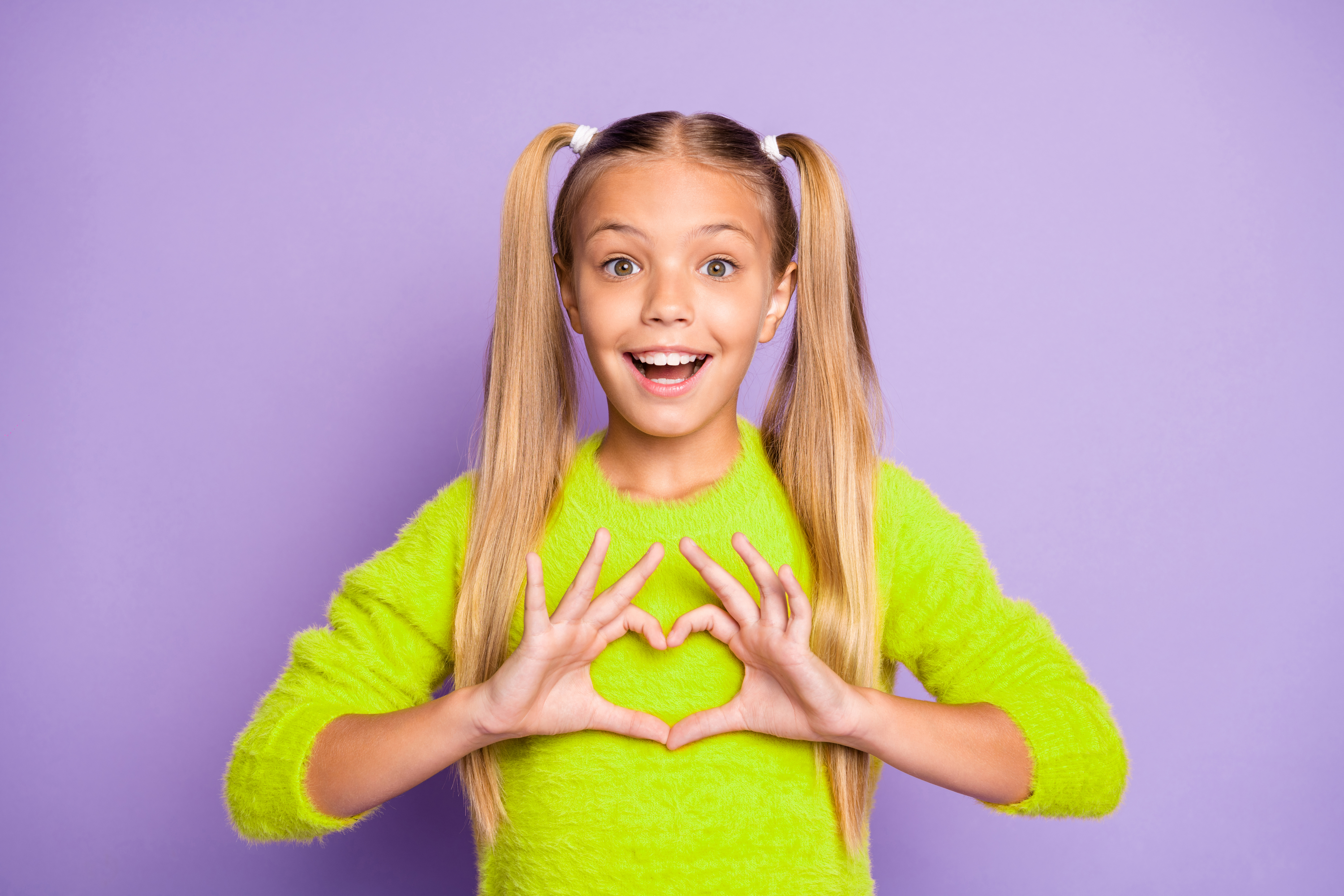 Photo of stylish trendy cheerful positive girl showing heart shape sign with emotions on face isolated in yellow sweater pastel violet color background